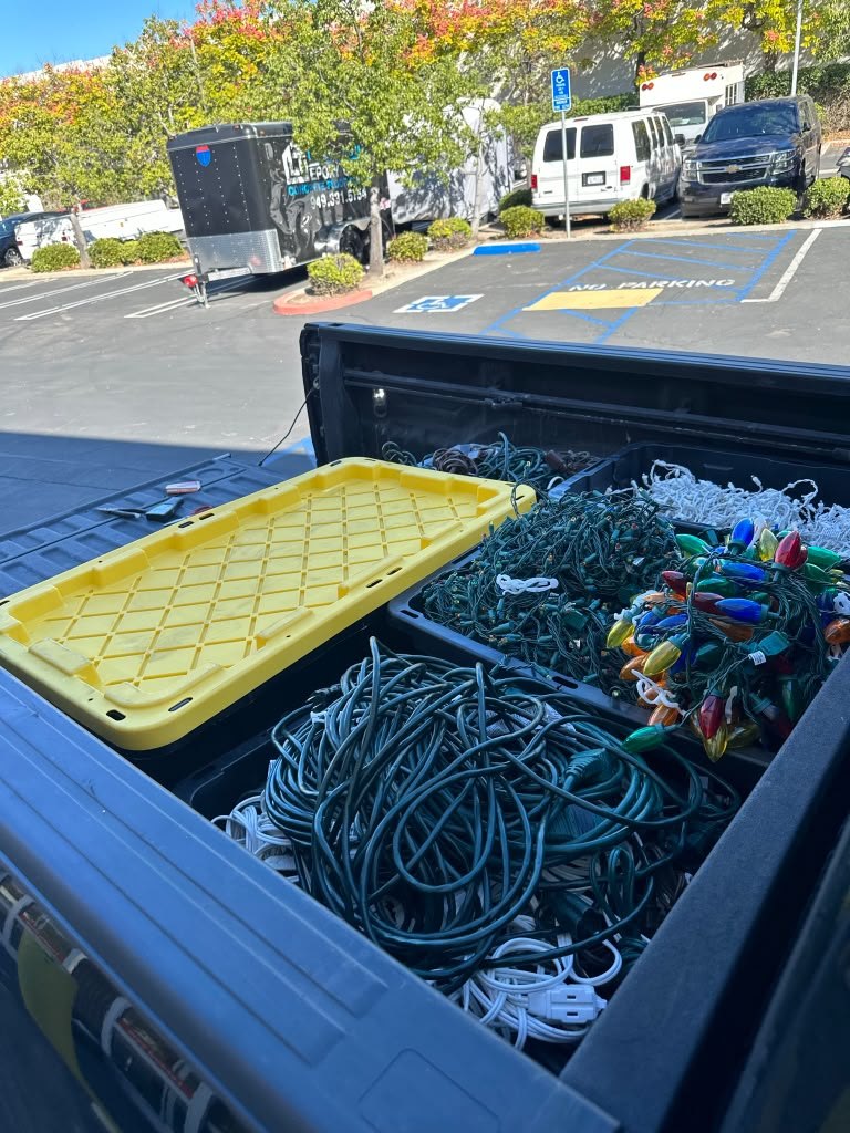 Christmas lights and installation supplies packed in storage bins in the back of a work truck.